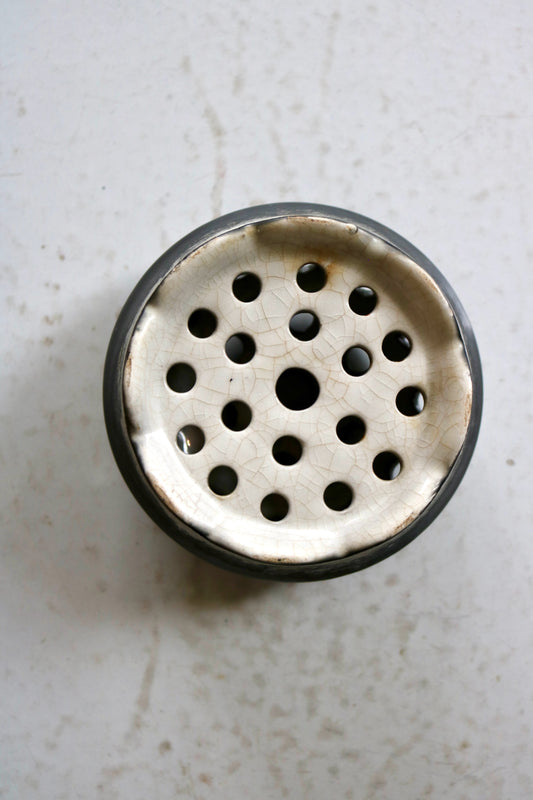 bottom of a black glazed ceramic vintage flower frog