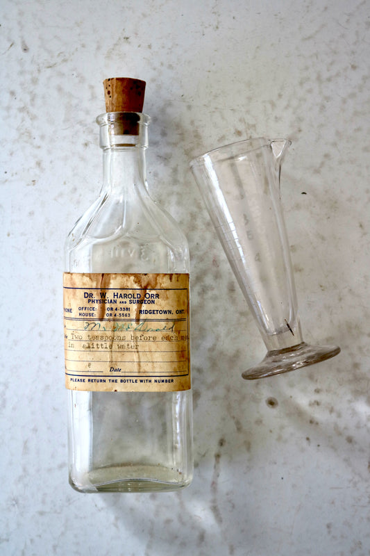 vintage glass apothecary medicine bottle and beaker or measure